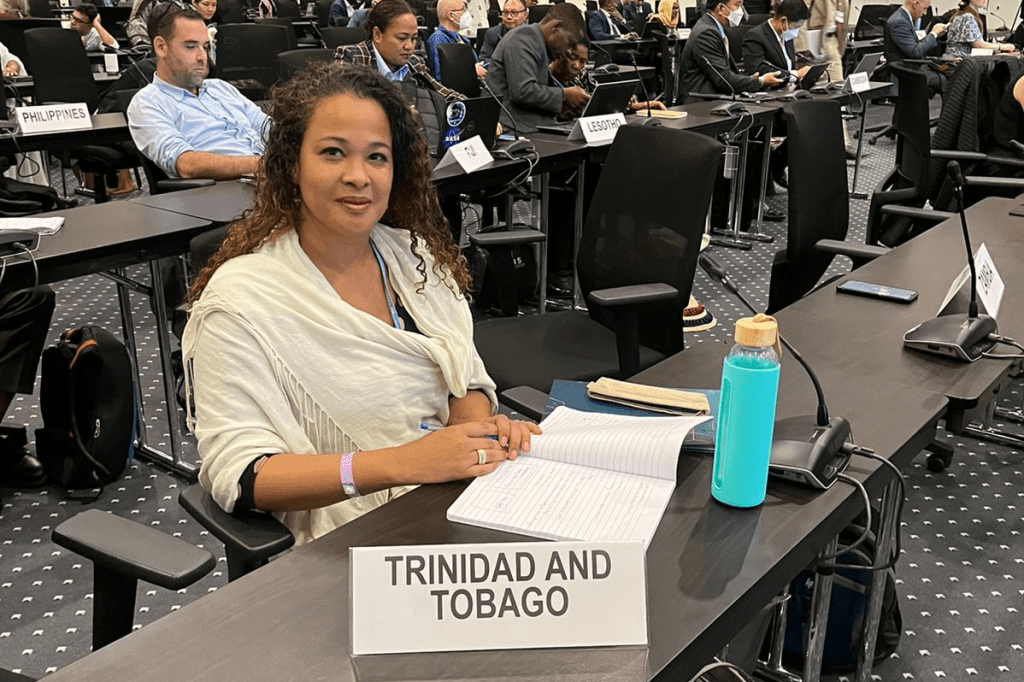 Caroline Mair-Toby, a negotiator for Trinidad and Tobago at COP27, sitting at a desk with a Trinidad and Tobago sign in front of her